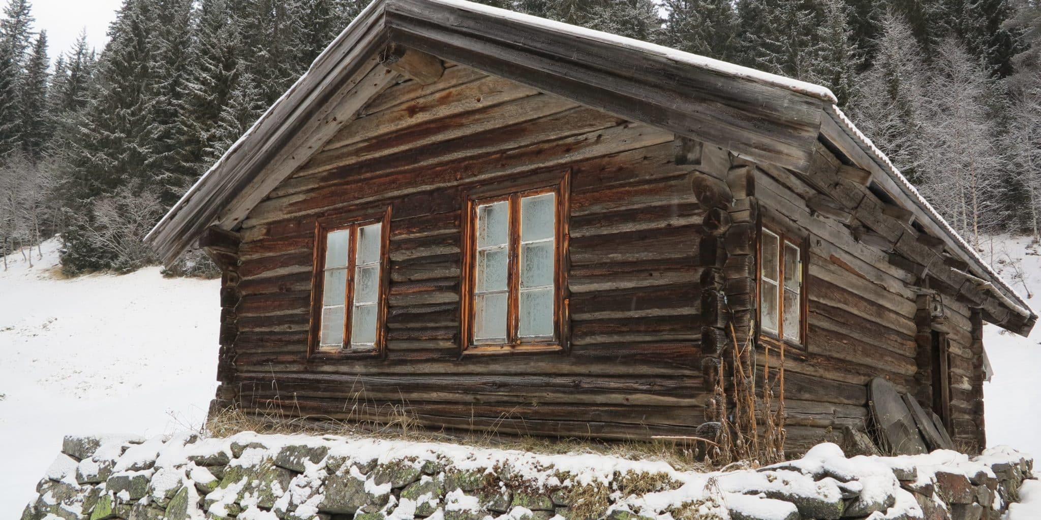 Gammel laftehytte i snøkledd skog