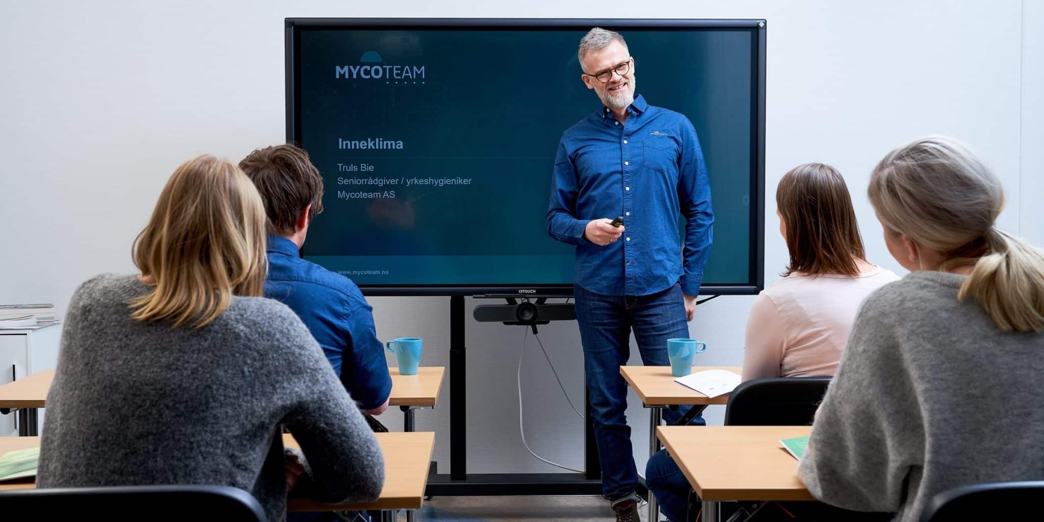 Mann i blå skjorte som holder et kurs